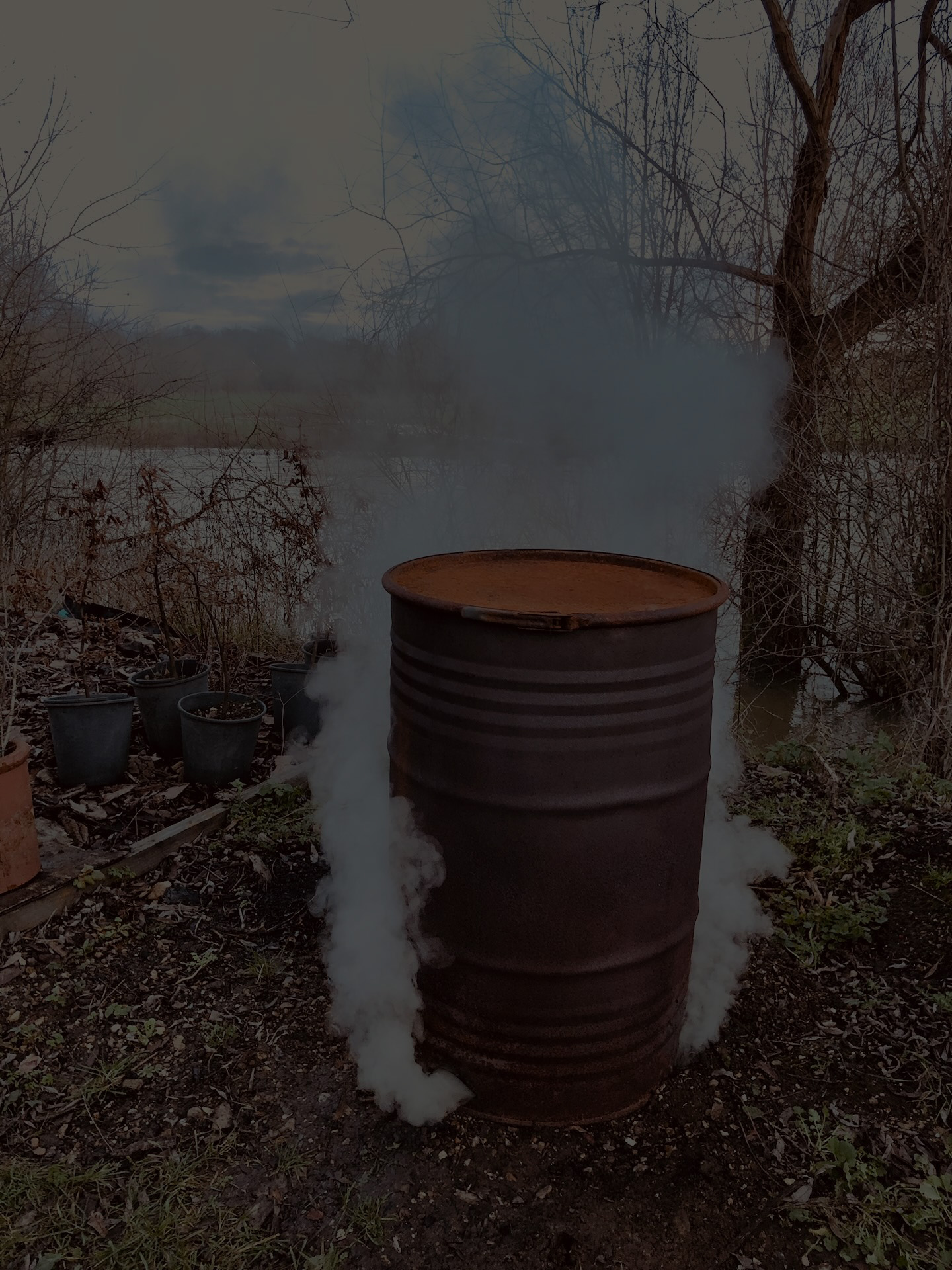 A smoking retort barrel beside the River Great Ouse on a misty morning